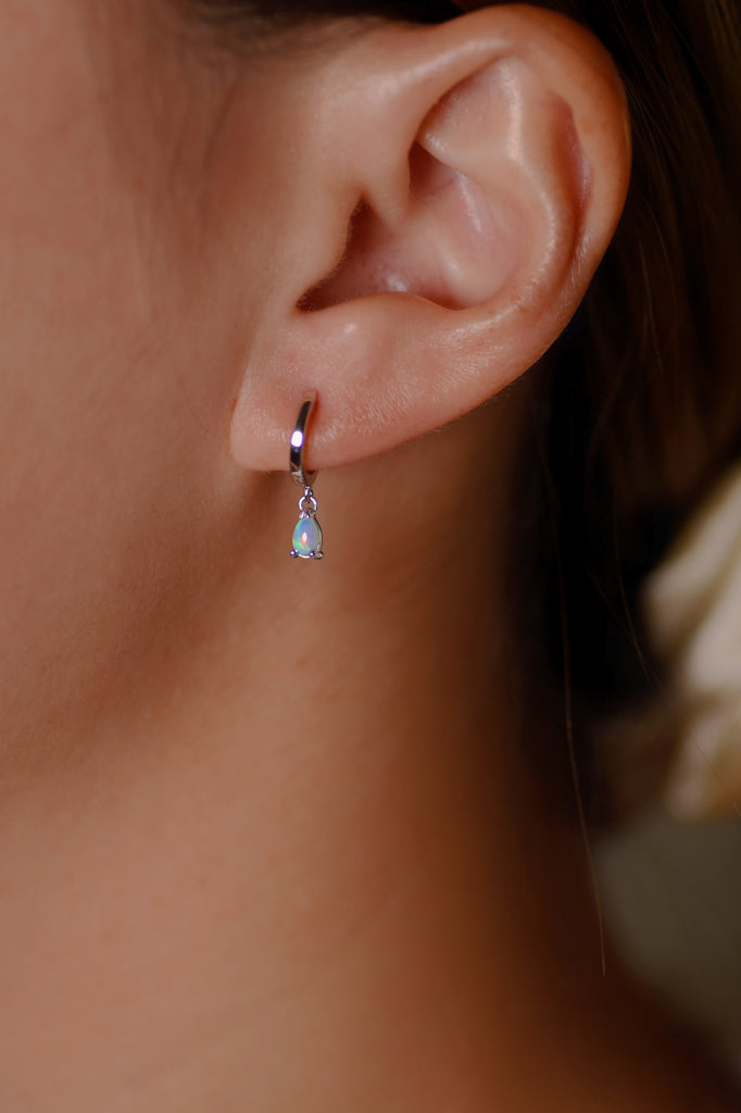 Model wearing Teardrop Opal Huggie Earrings in White Gold, Blue