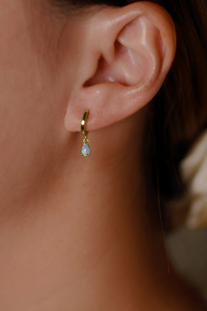 Model wearing Teardrop Opal Huggie Earrings in Yellow Gold, Blue