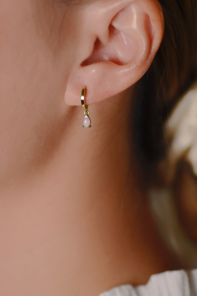 Model wearing Teardrop Opal Huggie Earrings in Yellow Gold, White
